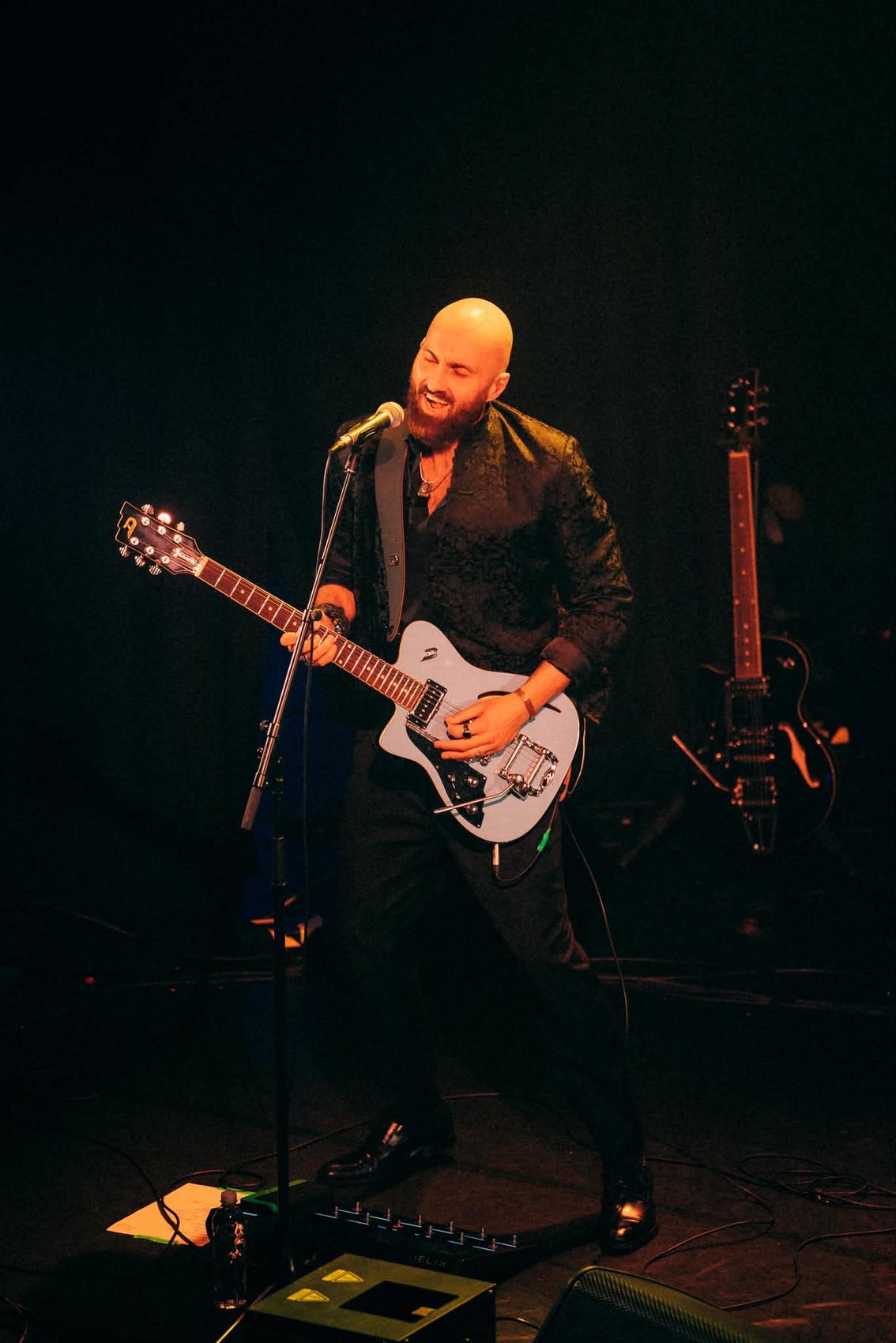Martin synger og spiller elektrisk gitar under et spotlys
